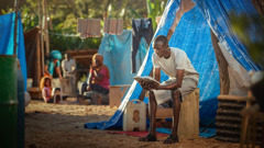 Un frère qui vit dans un camp de réfugiés lit la Bible.