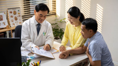 A doctor showing some printed information to a couple.