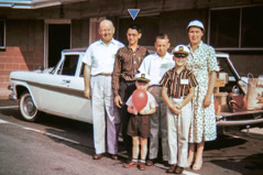 Russell as a teenager standing beside a station wagon with the Hutcheson family.