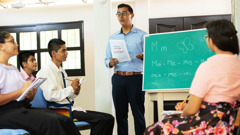 Um jovem participando em aulas de leitura na congregação. Ele faz anotações e escuta com atenção.