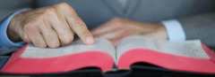 一个男人把手指放在书页上，一行一行地读圣经。