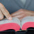 Mężczyzna palcem pomaga sobie śledzić czytany tekst Biblii.