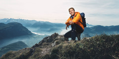Egy fiatal férfi boldogan néz szét a hegytetőről.