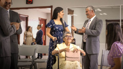 Um ancião elogiando uma irmã pela ajuda que ela dá a uma irmã na cadeira de rodas.