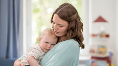 A mother holding her young son tenderly against her chest.