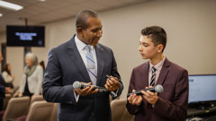 An elder showing a young brother at a Kingdom Hall how to change the batteries in the wireless microphones.