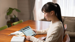 Una hermana joven hace su estudio personal. Tiene la Biblia abierta y ve un video en su tableta.