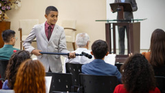 A young brother holding the microphone for a commenter during a congregation meeting.