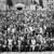 A large group of brothers and sisters posing for a photo outdoors at the 1925 convention in Indianapolis, Indiana.