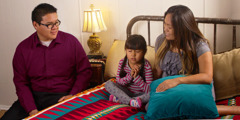 Parents listen as their young daughter prays before going to bed