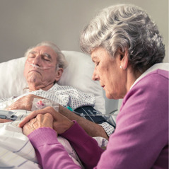 Una hermana preocupada ora junto a la cama de su esposo en el hospital