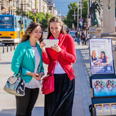 A sister stands beside a public witnessing cart and preaches to a woman