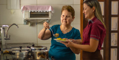 Maria Lúcia sert un de ses plats maison à une amie.