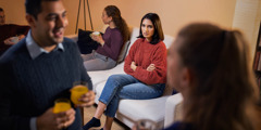 Una esposa mirant amb ressentiment el seu marit mentre ell parla amb una altra dona en una reunió social.