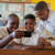 ثلاثة صبيان في المدرسة ينظرون بحماسة إلى الهاتف