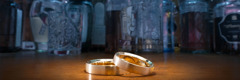 Two wedding rings and various bottles of alcohol on a table.