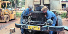 Темнокожий и белый брат ремонтируют машину.