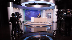 Broeders nemen de eerste uitzending van JW Broadcasting op, gepresenteerd door Stephen Lett.