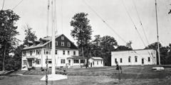 An exterior view of the WBBR radio station, showing the administration building, the power building, and the bottom of the transmitter mast.