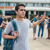 Un tânăr ridică mâna în semn de dezgust în timp ce se îndepărtează de școală și de un grup de elevi