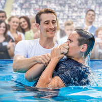 A young man getting baptized in a pool at a convention of Jehovah’s Witnesses.