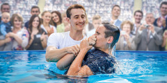 Um jovem sendo batizado numa piscina num congresso das Testemunhas de Jeová.