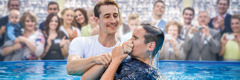 Auf einem Kongress von Jehovas Zeugen wird ein junger Mann in einem Wasserbecken getauft.