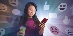 Una adolescente mira su celular. Se ven muchos emojis a su alrededor.