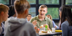 En gutt som snakker med noen klassekamerater i lunsjen.