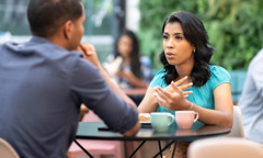 A jovem está conversando com o namorado dela em uma cafeteria ao ar livre.