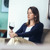 Uma mulher sozinha em casa olhando para uma taça de vinho.