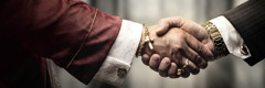 一名神职人员和一名商人握手，他们一个戴着奢华的金首饰，一个戴着名贵的金手表。