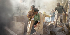 Egy tűzoltó segít a túlélőknek kimenekülni egy összeomlott épület romjai közül.