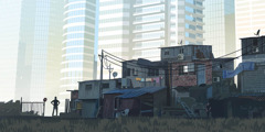 A man standing amid shanties looking toward luxury high-rise apartments.