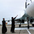 Un sacerdote bendice un avión de combate echándole agua bendita.