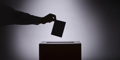 Una persona deposita su voto en una urna electoral.