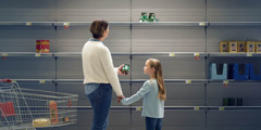 A mother and her young daughter surveying the bare shelves of a supermarket.