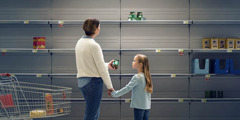 A mother and her young daughter surveying the bare shelves of a supermarket.