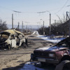 An abandoned road in a war-torn village in Ukraine, littered with bombed-out vehicles.