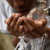 Un garçon boit dans ses mains l’eau d’un robinet.