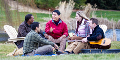 Fünf junge Erwachsene sitzen draußen und genießen die gemeinsame Zeit.