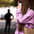 A criminal stalking a woman who is alone. She sees the criminal behind her and uses her mobile phone to call for help.