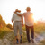 Two elderly men walking together down a path at sunset. One has his arm on the shoulder of the other.