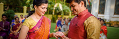 Uma noiva e um noivo casam-se num local ao ar livre. O noivo coloca uma aliança no dedo da noiva.