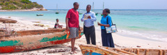 En la playa, una pareja de testigos de Jehová le ofrece una revista a un hombre.