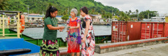 Two of Jehovah’s Witnesses offering a tract to a woman near a docked container barge.