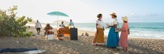 Two Witnesses conversing with a woman on a popular beach.