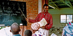 Jehovov svedok učí skupinu ľudí počas kurzu čítania a písania.