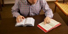 Um homem comparando duas traduções da Bíblia