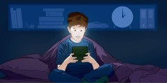 A young boy sitting up in bed playing a video game